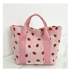 Close-up detail of pink corduroy fabric and handles on strawberry printed tote bag