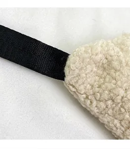 Detailed view showing the durable shoulder strap connection on a white plush crossbody bag