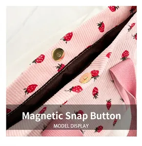 Detailed view of the magnetic snap closure on a pink strawberry print corduroy bag