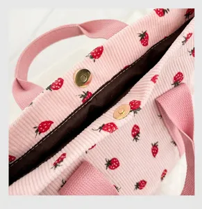 Detailweergave van de magneetsluiting op een roze corduroy tas met aardbeienprint