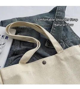 Detail of cream canvas tote bag showing durable shoulder straps and metal snap button
