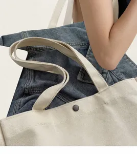 Detail der cremefarbenen Canvas-Tasche mit robusten Trägern und Metalldruckknopf