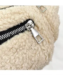Close-up of smooth metal zipper head on a cream plush fleece shoulder bag