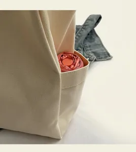 Detailaufnahme der Seitentasche einer cremefarbenen Canvas-Tragetasche mit praktischem Stauraum