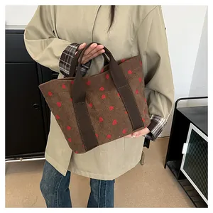 Detail view of brown corduroy tote bag with cute red strawberry print pattern