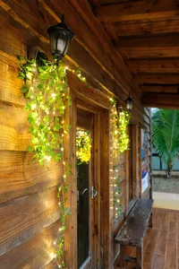 Warmweiße LED-Rankenlichter mit künstlichen grünen Blättern auf einer rustikalen Veranda