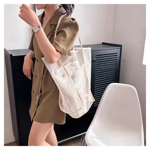 Detail view of a model carrying a large white mesh tote bag for beach and travel storage