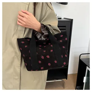 Detail view of a black corduroy tote bag with cute pink strawberry patterns