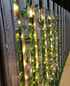Nahaufnahme von künstlichen Efeublatt-Lichterketten an einem hölzernen Gartenzaun