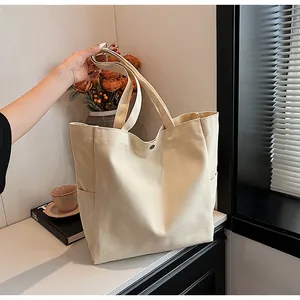 Minimalist beige canvas tote bag with side pockets in a warm lifestyle setting