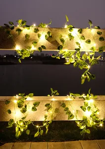 Warme LED-Lichterkette mit künstlichen Efeublättern an einem Steinpfosten in der Nacht.