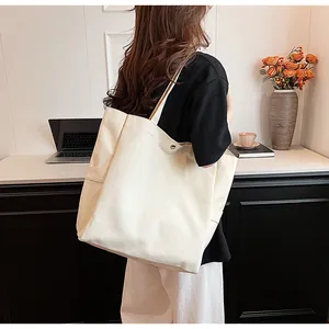 Detailed side view of a minimalist large white canvas tote bag carried by a female model.