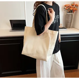 Close-up of a minimalist beige canvas tote bag carried by a model in a stylish interior