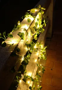 Detailansicht der warmen LED-Lichterkette mit künstlichen grünen Blättern am Geländer.