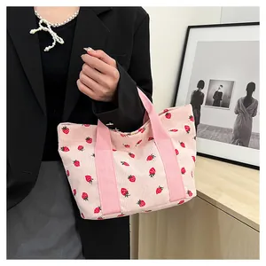 Close-up of pink corduroy tote bag featuring a cute strawberry print and soft texture