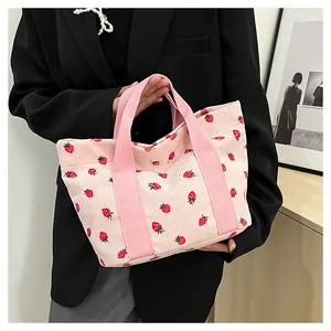 Detailed view of pink corduroy tote bag featuring cute red strawberry prints