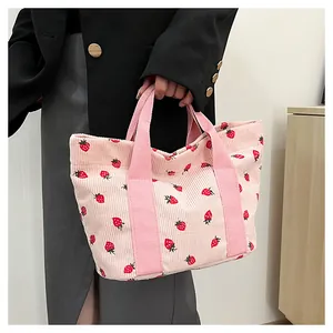 Detailed view of a stylish pink corduroy tote bag with cute strawberry patterns.