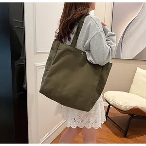Detail view of the large olive green canvas tote bag carried over the shoulder