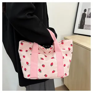 Close-up detail of a large capacity pink corduroy tote bag with cute strawberry prints.