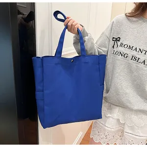 Woman holding a royal blue canvas tote bag with snap closure in an indoor setting