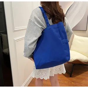 Back view of a stylish woman carrying a large cobalt blue canvas tote shoulder bag