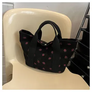 Detailed view of black corduroy tote bag with cute red strawberry print pattern