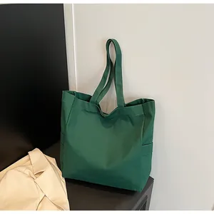 Full view of minimalist green canvas tote bag leaning against a stylish interior wall