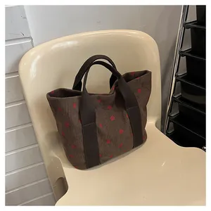 Detailed side view of a brown corduroy tote bag featuring a cute red strawberry pattern