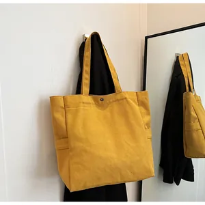 Simple bright yellow canvas tote bag hanging on a hook in a minimalist indoor setting