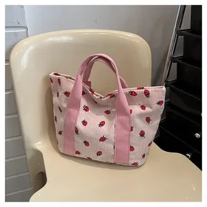 Detailed view of a stylish pink corduroy tote bag featuring cute strawberry patterns