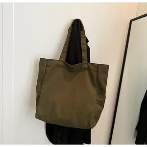 Detailed view of an olive green canvas tote bag hanging on a wall, showing texture