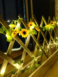 Nahaufnahme von Solar-Sonnenblumen- und Efeu-LED-Lichterketten an einem weißen Gartenzaun