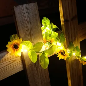 Nahaufnahme von warmweißen LED-Sonnenblumen-Lichterketten an einem hölzernen Gartenzaun