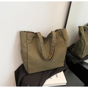 Detailed view of an olive green canvas tote bag with side pockets in a lifestyle set