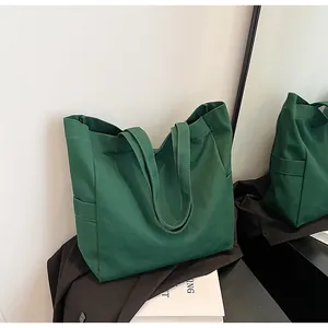 Stylish dark green canvas tote bag presented in a minimalist indoor setting with mirror