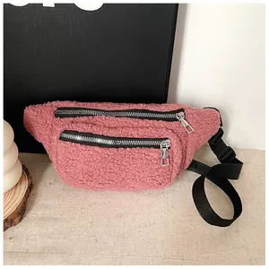 Detail view of pink plush waist bag with double silver zippers and black adjustable strap.