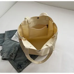 Detail view of cream canvas tote bag interior showing zipper pocket and snap closure