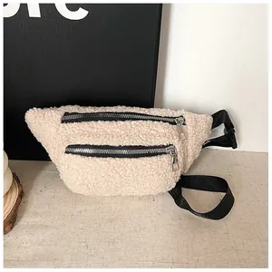 Close-up detail of a cream fuzzy fleece waist bag featuring dual silver-toned zippers