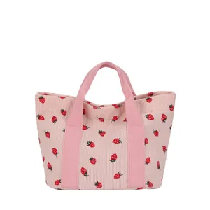 Pink corduroy tote bag with strawberry print pattern on white background