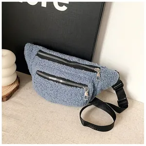 Close-up of a light blue sherpa belt bag with dual silver zippers and a black strap.