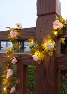 LED-Rosenranken-Lichterkette an einem Holzzaun in der Abenddämmerung
