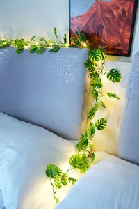 Detail der grünen Monstera-Blatt-LED-Rankenlichter an einem Kopfteil im Schlafzimmer.