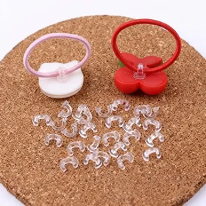 Close-up of small transparent plastic DIY hair clip connector parts on a brown cork board