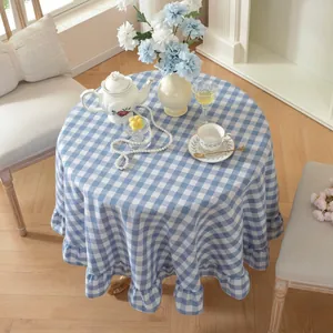 Close-up view of a blue and white checkered round tablecloth with elegant ruffle edges