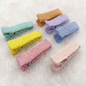 Detail view of seven colorful knitted alligator hair clips on white fuzzy background