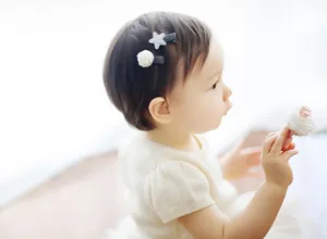 Detailed view of handmade mesh ball and star hair clips worn by a baby girl