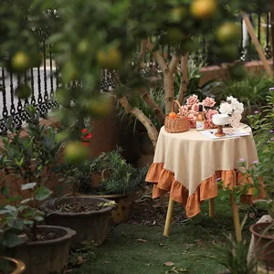 Modern minimalist ruffled round tablecloth with orange lotus leaf edge detail in a garden setting
