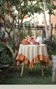 Modern minimalist beige and orange ruffled tablecloth presented in a romantic garden setting