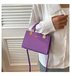 Detail view of a purple litchi texture handbag with a braided handle and gold hardware