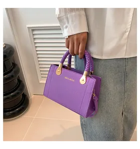 Purple textured faux leather handbag featuring braided handles and gold-tone hardware